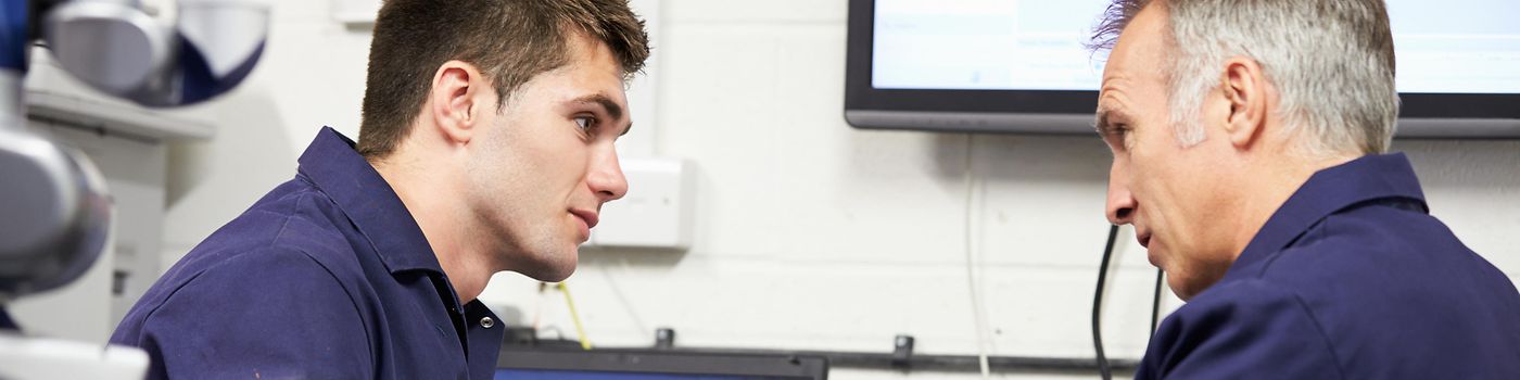 Engineer Showing Trainee Plans With CMM Arm In Foreground