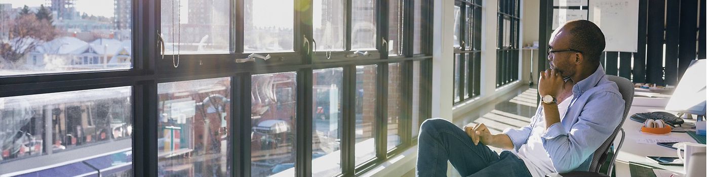 Man sitting in office looks out window to city skyline