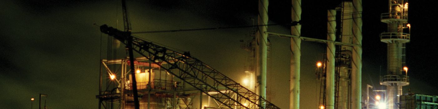 Pipelines and a storage tank at a process plant lit up at night